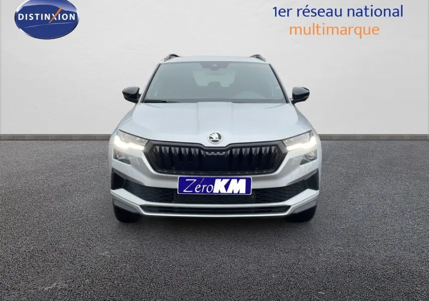Vue frontale d'un Skoda Karoq gris argent métal 2025 avec calandre noire et feux LED allumés.