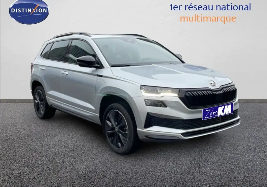 Vue 3/4 avant d’un Skoda Karoq gris argent métal 2025 avec jantes noires et calandre noire sportive.