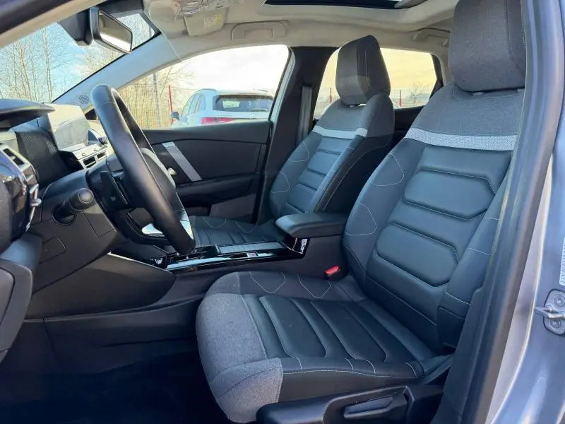 Vue intérieure côté conducteur de la Citroën C4 2024 gris acier, montrant les sièges avant et le tableau de bord moderne.
