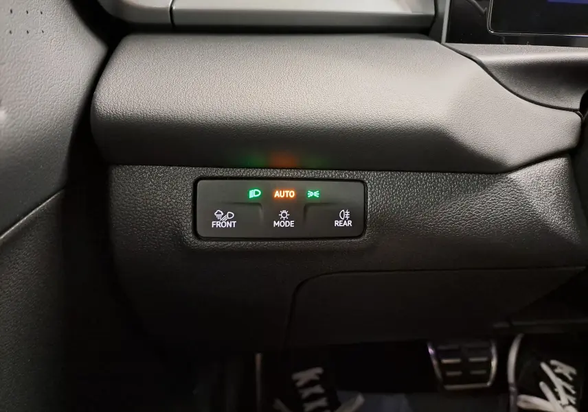 Détail du tableau de bord noir du Volkswagen T-Roc 2026 avec commandes d’éclairage automatiques et voyants allumés.