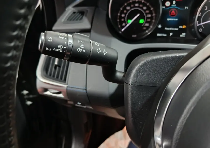 Gros plan sur la commande des phares et clignotants à gauche du volant cuir noir du Jaguar E-PACE P200 2019.