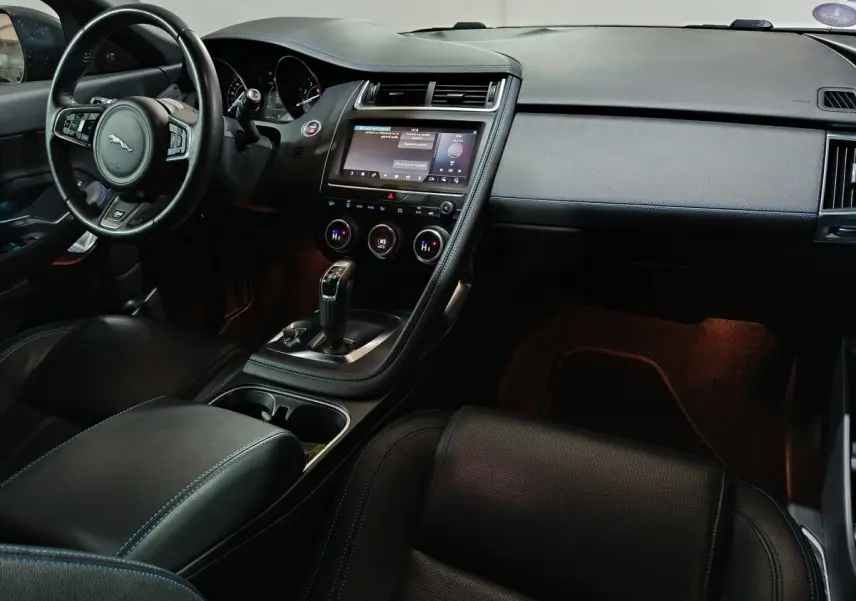 Intérieur noir de la Jaguar E-PACE 2019, vue côté conducteur, avec tableau de bord et écran tactile central lumineux.