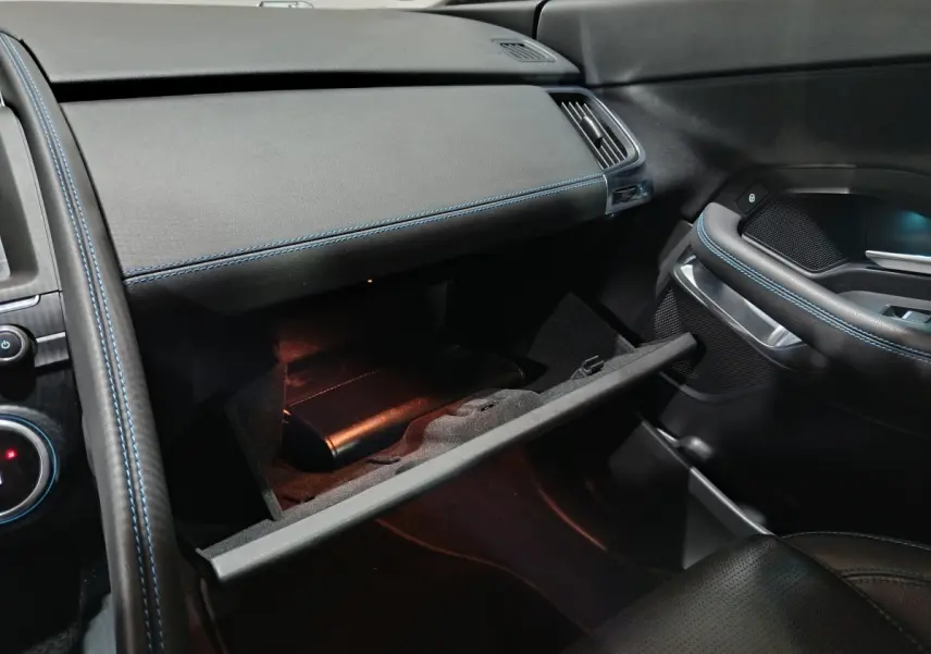 Intérieur noir du Jaguar E-PACE 2019, vue côté passager avec boîte à gants ouverte et surpiqûres bleues.