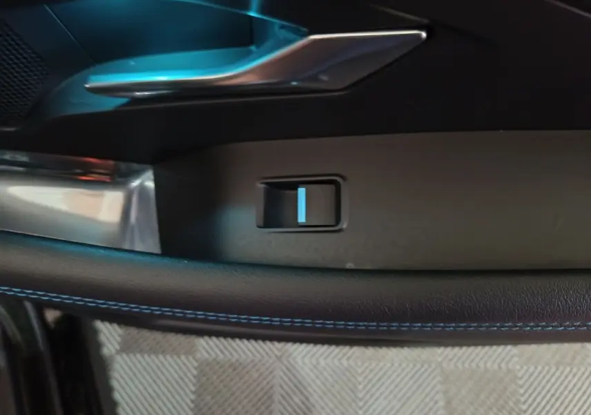 Détail de la poignée intérieure côté gauche avec couture bleue sur le cuir dans un Jaguar E-PACE noir.