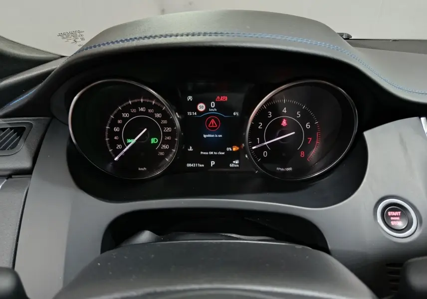 Vue rapprochée du tableau de bord noir du Jaguar E-PACE 2019 avec compteurs analogiques et écran digital central allumé.