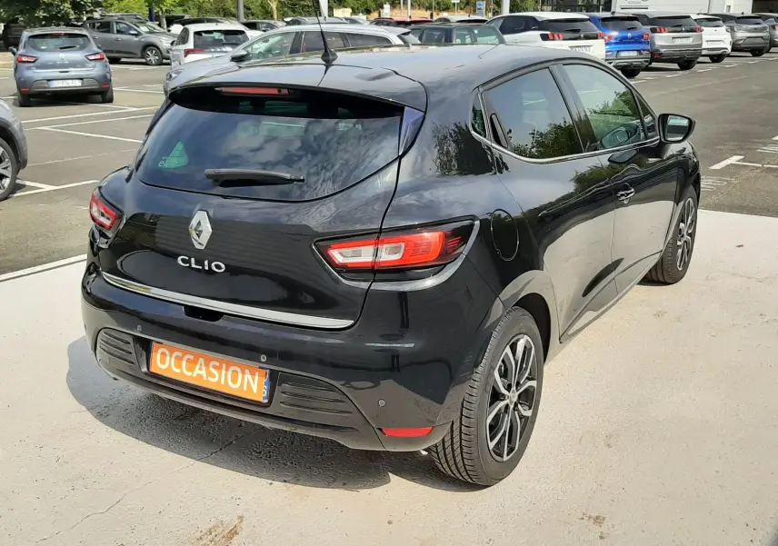 Vue 3/4 arrière droite d'une Renault Clio IV noire de 2018 avec feux LED et plaque "OCCASION" visible.