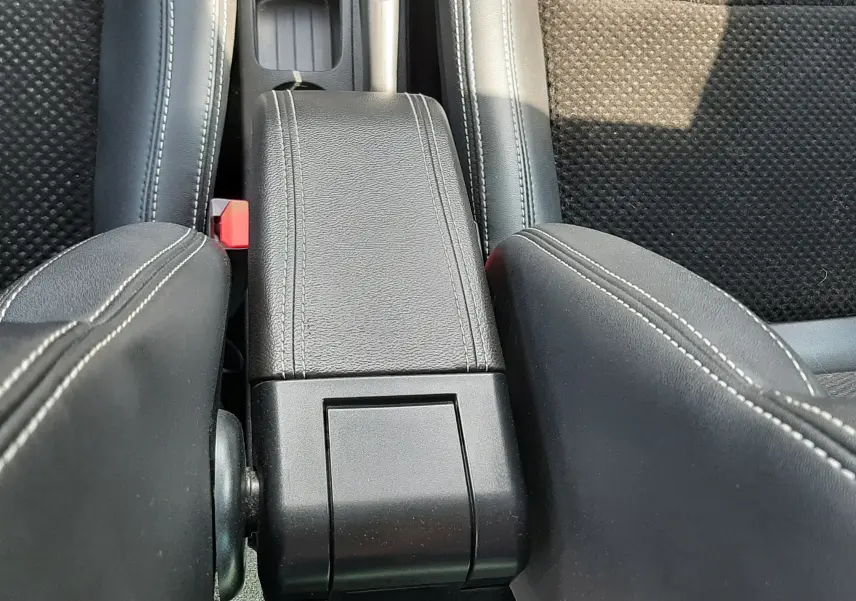 Vue plongeante sur l'accoudoir central noir et les sièges tissu noir de la Renault Clio IV 0.9 TCE 90 Intens de 2018.