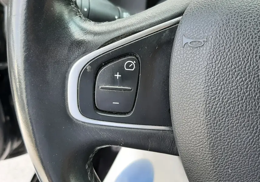 Gros plan sur les commandes de régulateur de vitesse au volant noir d'une Renault Clio IV 0.9 TCE 90 Intens de 2018.