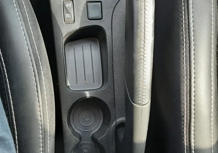 Vue plongeante sur la console centrale noire de la Renault Clio IV avec frein à main, bouton ECO et porte-gobelets.