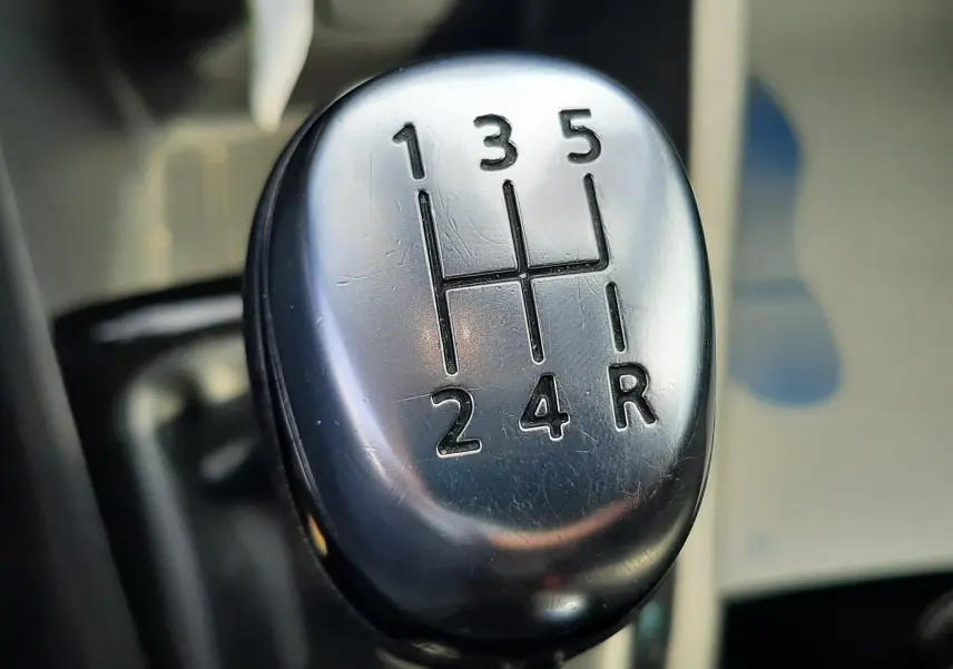 Gros plan sur le levier de vitesse manuel argenté de la Renault Clio IV noire, montrant les rapports 1 à 5 et la marche arrière.