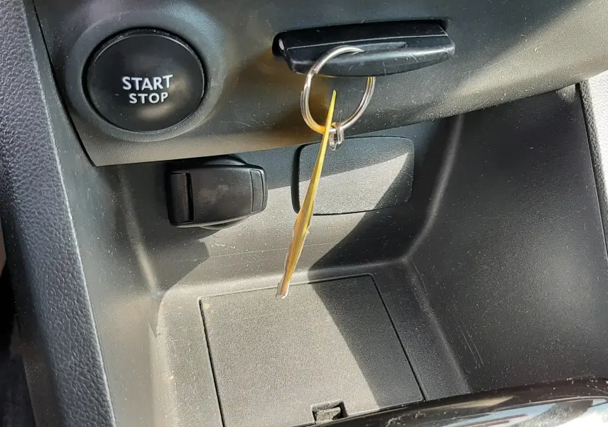 Gros plan intérieur sur la console centrale noire de la Renault Clio IV avec clé insérée et bouton Start Stop visible.