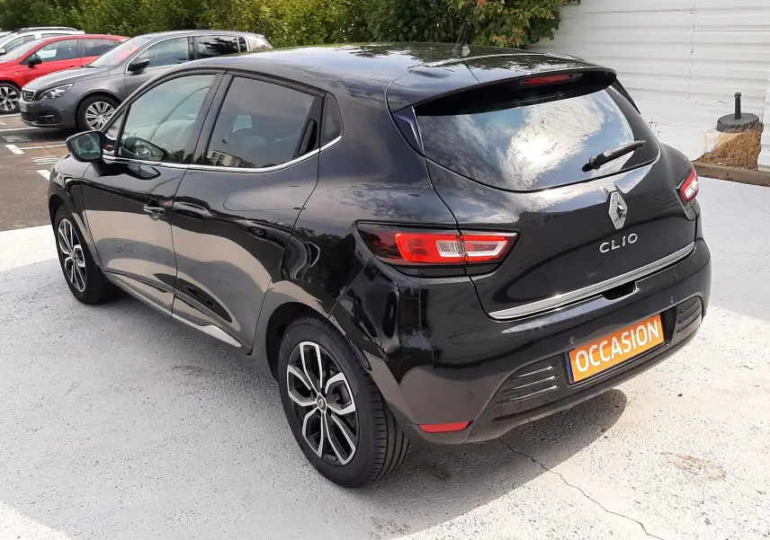 Vue 3/4 arrière droite d'une Renault Clio IV noire, avec jantes alliage et feux arrière LED, stationnée sur parking.