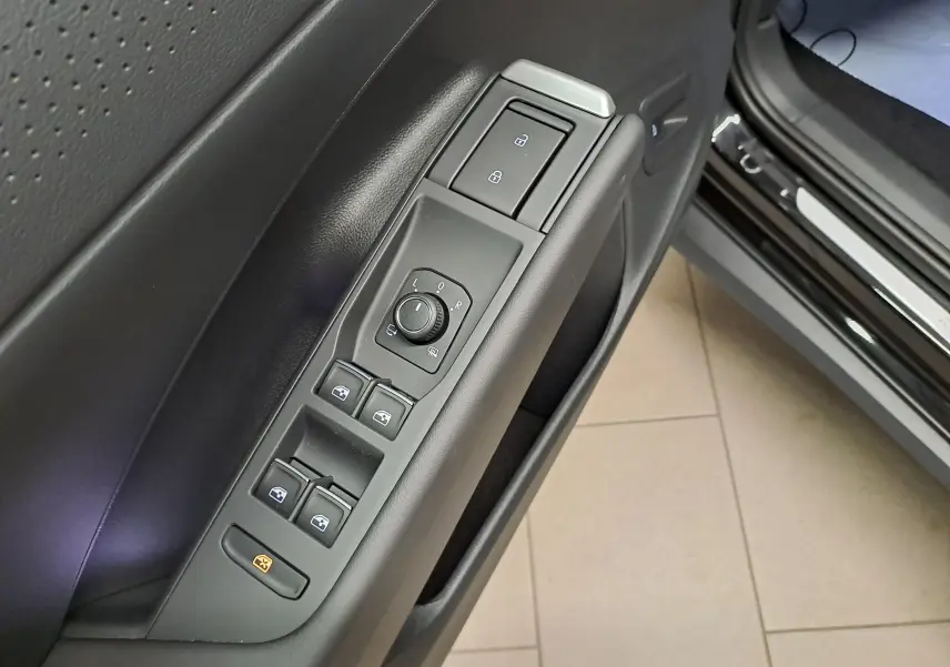 Gros plan sur les commandes de lève-vitres et rétroviseurs sur la porte côté conducteur du Volkswagen T-Roc noir ébène 2026.