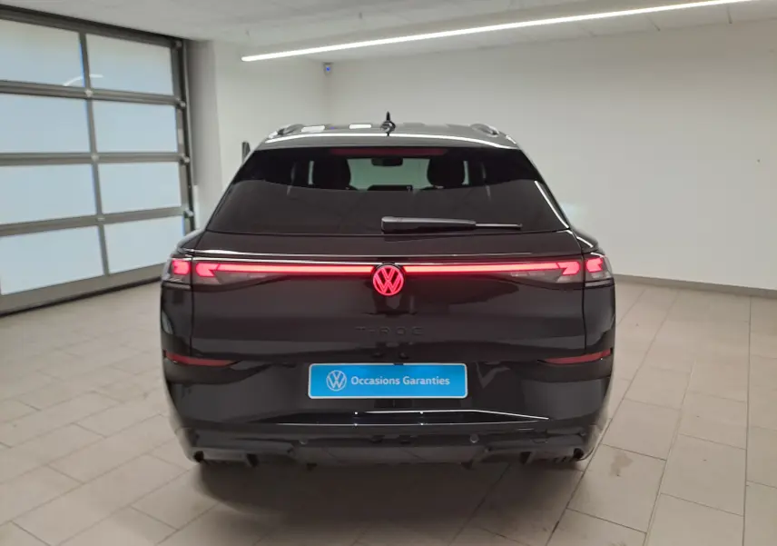 Vue arrière du Volkswagen T-Roc 2026 noir ébène avec feux LED allumés et logo lumineux au centre du hayon.