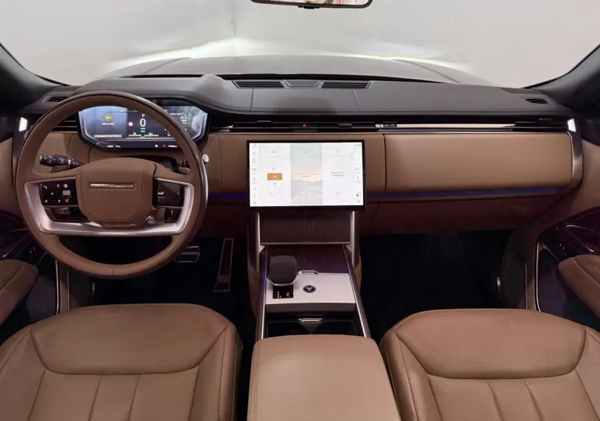 Vue intérieure avant du Range Rover PHEV 2024 avec tableau de bord noir et sièges cuir marron clair.