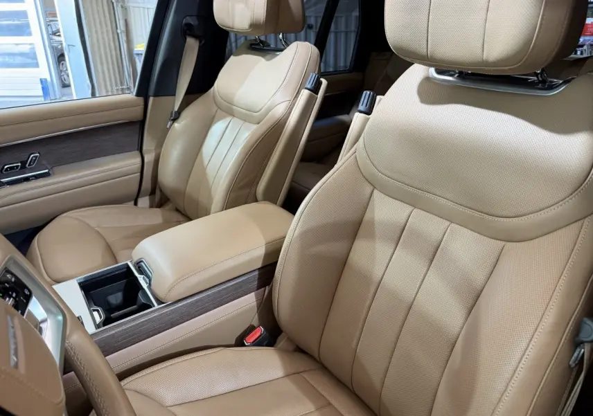 Vue intérieure rapprochée des sièges avant en cuir beige du Range Rover PHEV P550e Autobiography 2024.