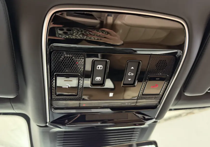 Vue intérieure du plafonnier noir brillant du Range Rover PHEV 2024 avec commandes de toit ouvrant et SOS.