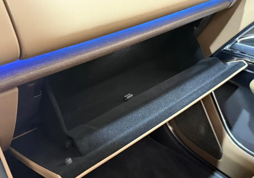 Vue intérieure rapprochée de la boîte à gants ouverte du Range Rover PHEV P550e Autobiography SWB 2024 avec finition cuir beige.