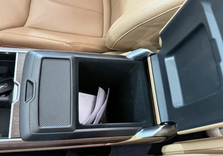 Vue rapprochée de la console centrale ouverte du Range Rover PHEV 2024, cuir beige et insert bois visible.