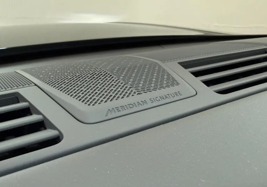 Gros plan sur la grille d'enceinte Meridian Signature intégrée au tableau de bord du Range Rover PHEV noir.