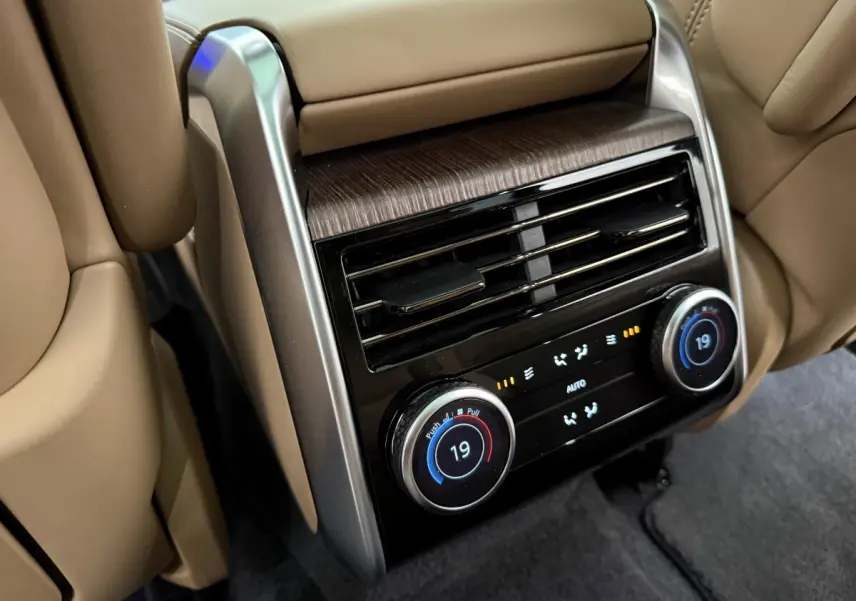 Détail de la console de climatisation arrière beige du Range Rover PHEV 2024 avec commandes digitales et aérateurs.