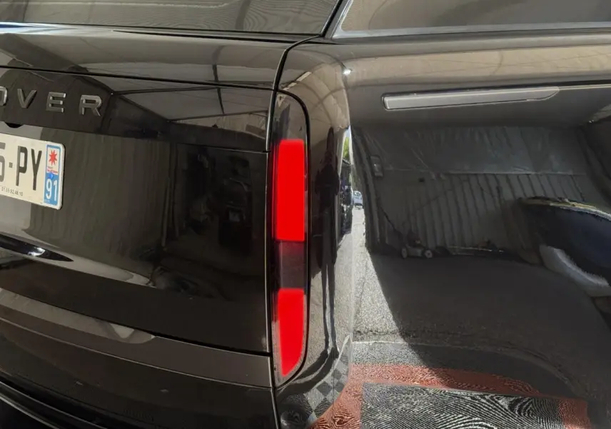 Gros plan sur le feu arrière droit noir brillant du Range Rover PHEV P550e 2024 avec plaque d’immatriculation française.