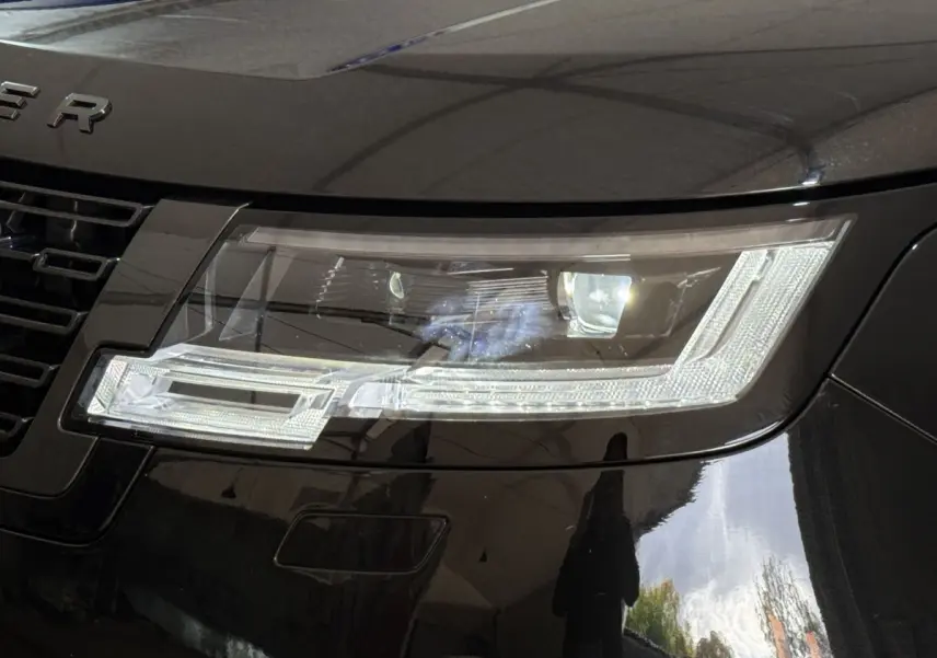 Gros plan sur le phare avant droit du Range Rover PHEV P550e noir, mettant en valeur son design LED moderne.