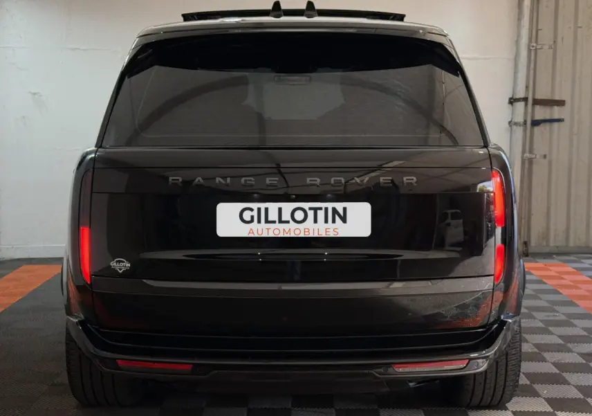 Vue arrière d'un Range Rover PHEV P550e Autobiography noir 2024 avec feux verticaux et logo visible.