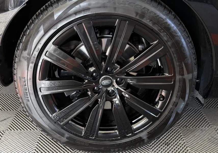 Gros plan sur la roue avant droite noire brillante du Range Rover PHEV P550e 2024 avec logo Land Rover central.