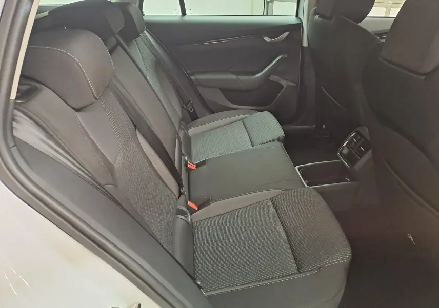 Vue intérieure côté gauche des sièges arrière noirs en tissu de la Skoda Octavia Combi 2025, avec accoudoir central et aérateurs.