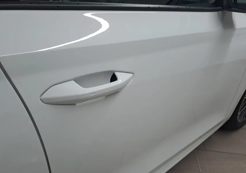 Gros plan sur la poignée de porte côté avant gauche de la Skoda Octavia Combi blanc Moon avec jante alliage visible.
