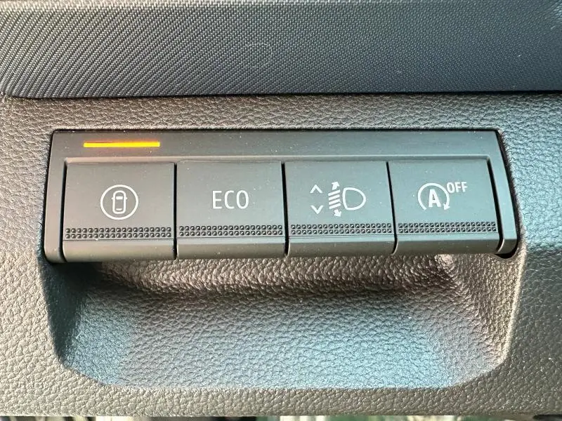 Gros plan sur les boutons de commande du tableau de bord du Dacia Bigster 2025, avec témoin lumineux orange actif.