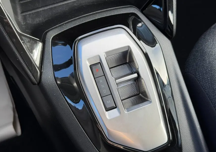 Gros plan sur la commande de boîte automatique argentée entourée de noir brillant dans l’habitacle du Peugeot 208 gris Artense.
