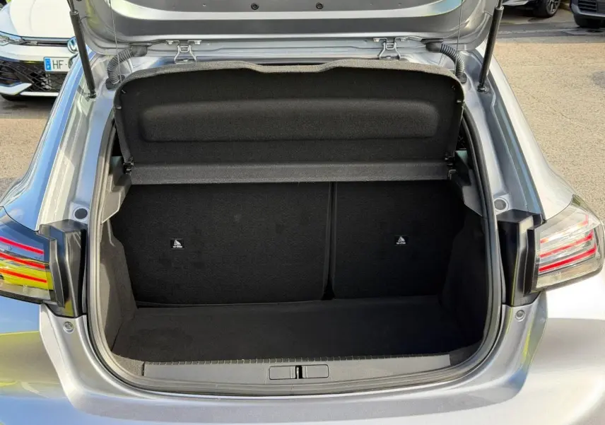 Coffre ouvert vu de l'arrière d'une Peugeot 208 gris Artense 2025, montrant l'espace de rangement vide.
