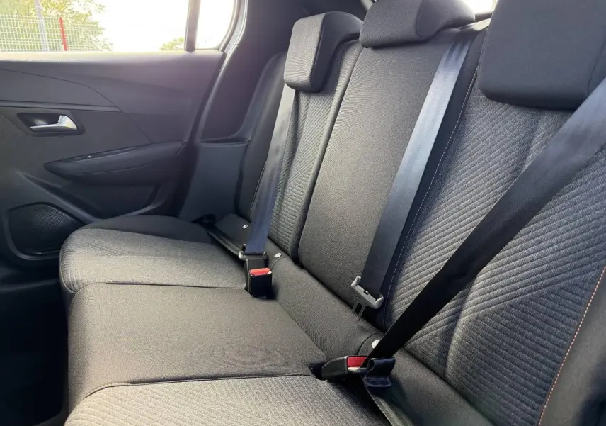 Vue intérieure côté droit sur la banquette arrière en tissu gris avec surpiqûres orange de la Peugeot 208 1.2 Hybrid 2025.