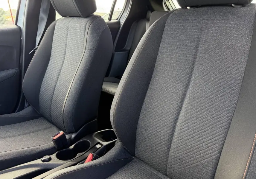 Gros plan sur les sièges avant en tissu gris avec surpiqûres orange de la Peugeot 208 1.2 Hybrid 110ch Style.