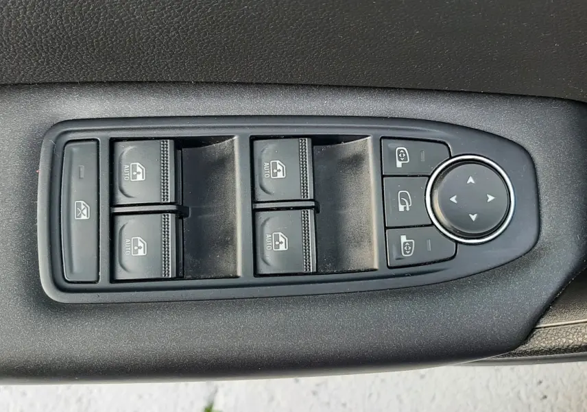 Panneau de commandes des vitres et rétroviseurs noirs sur la porte intérieure d'un Renault Captur bleu iron toit noir.