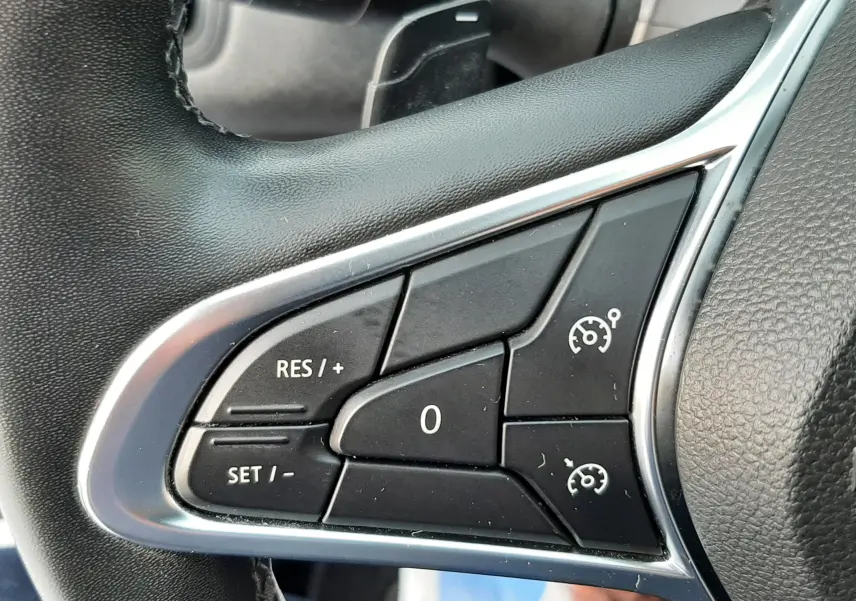 Gros plan sur les commandes de régulateur de vitesse au volant noir du Renault Captur bleu iron 2020.