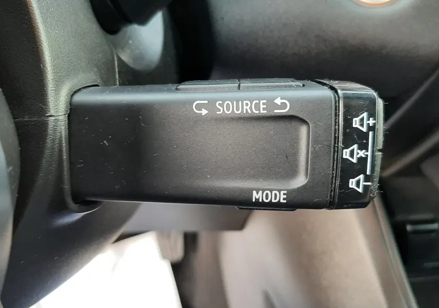 Gros plan sur la commande au volant du Renault Captur 2020, bouton source et mode visibles, intérieur noir.