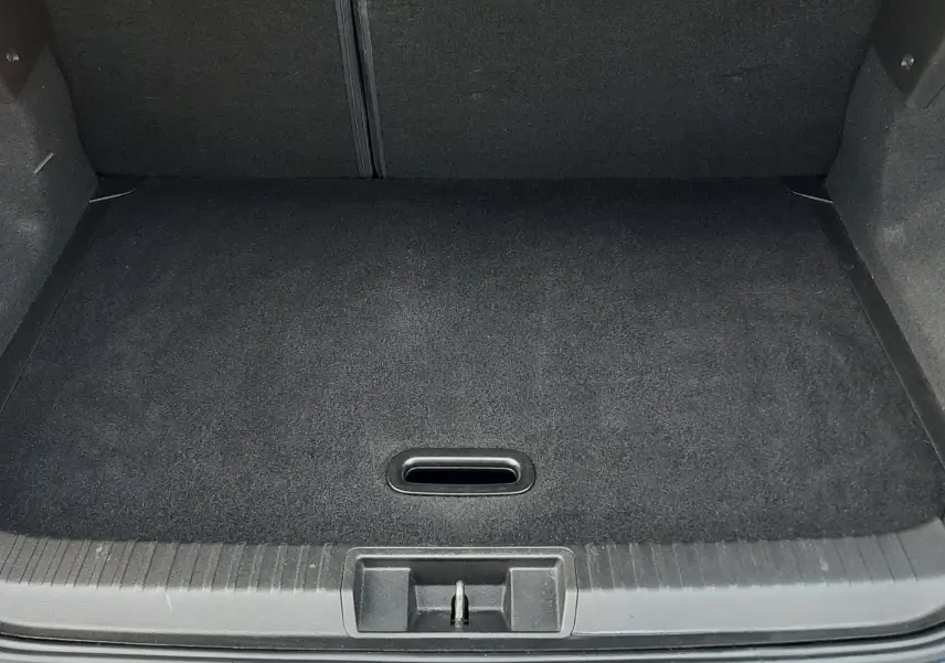 Coffre ouvert vu de l'arrière d'un Renault Captur bleu iron avec intérieur noir et tapis de coffre propre.