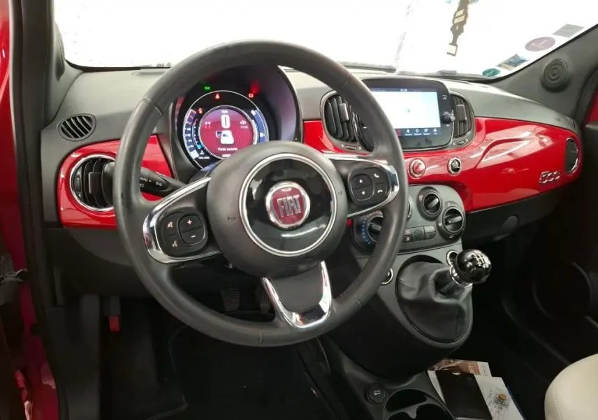 Vue intérieure avant de la FIAT 500 Dolcevita rouge, volant multifonction et tableau de bord brillant avec écran tactile.