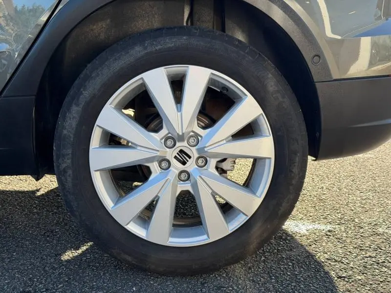 Gros plan sur la roue avant gauche d’un SEAT Arona 2025, jante alliage argentée avec logo SEAT au centre.