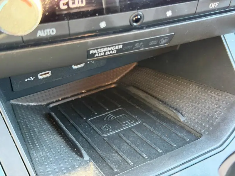 Gros plan sur la console centrale noire du SEAT Arona 2025, montrant le chargeur sans fil et les ports USB.