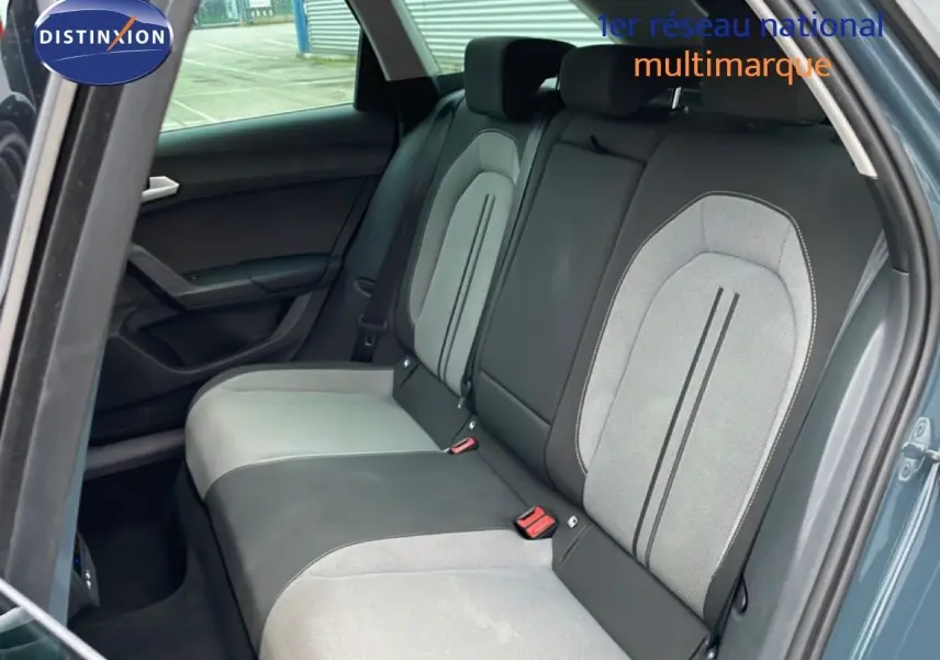 Vue intérieure côté arrière droit du SEAT Leon gris Fiord, mettant en valeur les sièges arrière bi-matière gris clair et foncé.