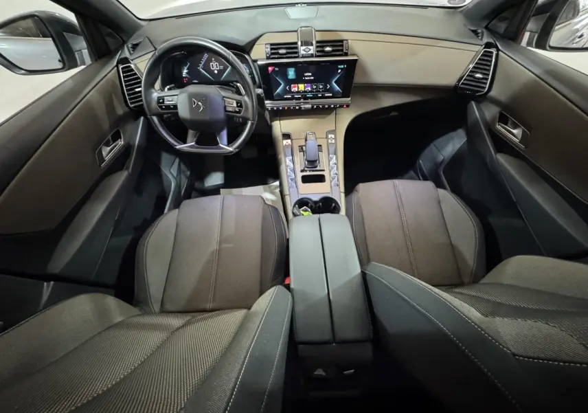Vue intérieure avant du DS7 Crossback E-TENSE gris foncé, avec volant cuir multifonctions et écran tactile central lumineux.