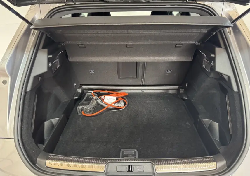 Coffre ouvert d’un DS7 Crossback gris foncé, vue de dessus montrant la trappe à ski et le câble de recharge hybride.