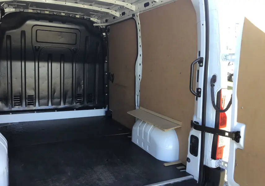 Vue intérieure arrière du Renault Master blanc L1H1 2023, montrant l'espace de chargement avec parois en bois et sol noir antidérapant.