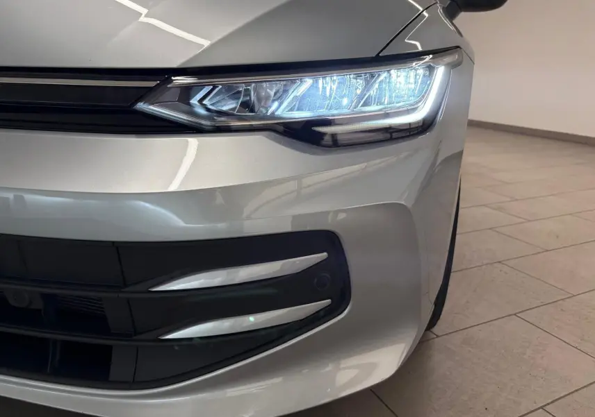 Gros plan sur l'avant droit d'une Volkswagen Golf 2.0 TDI 116 BVM6 Life Plus 2025 en reflet argent avec phares allumés.