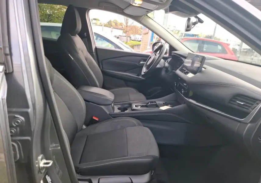 Vue intérieure côté gauche du Nissan Qashqai e-POWER 2023 gris foncé, montrant les sièges avant et le tableau de bord moderne.