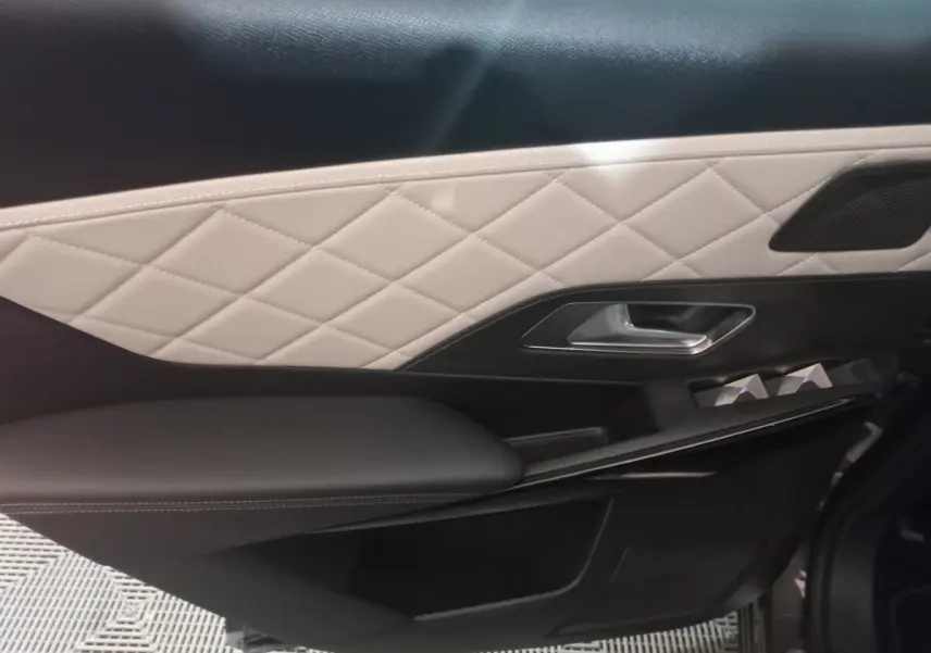 Détail de la porte intérieure côté droit du DS7 Crossback 2021 avec cuir beige matelassé et accoudoir noir.